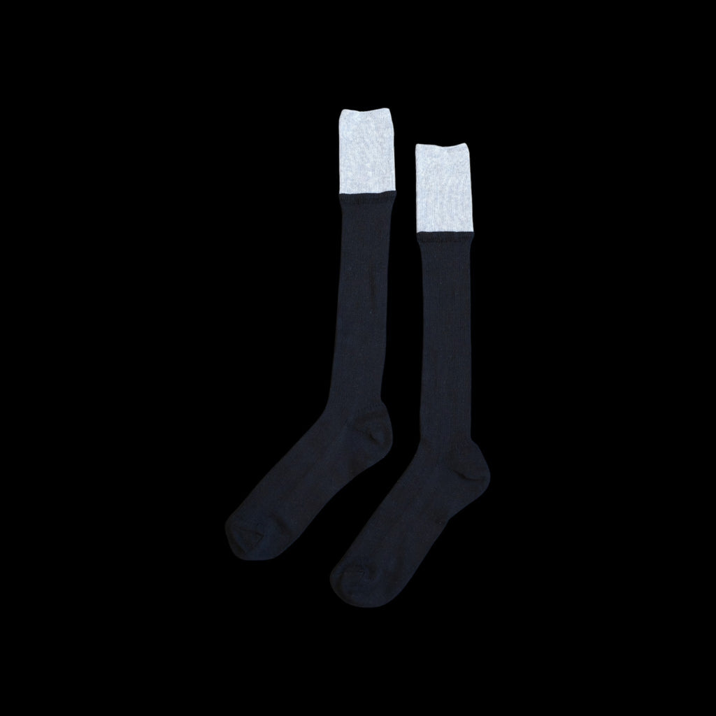 SUNMOOL black knee-high socks with a contrasting grey dip-dyed cuff and ribbed texture on a black background.