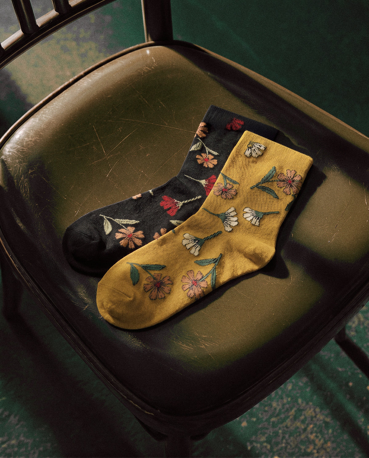 SUNMOOL Dear Wild Flower socks in black and mustard with botanical floral embroidery on a vintage chair.