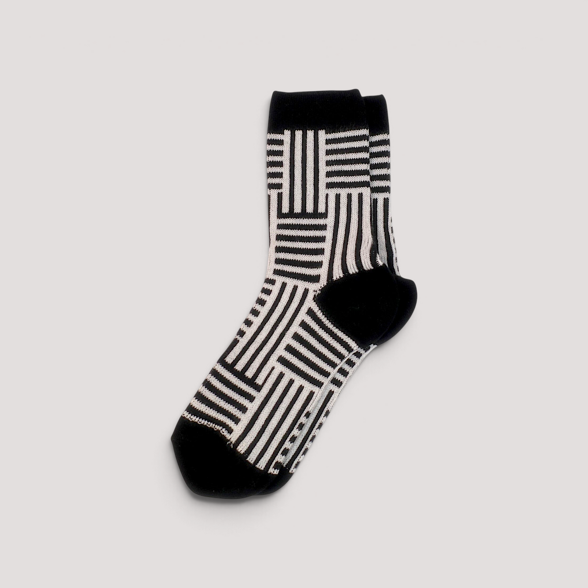 SUNMOOL crew socks featuring a black and white geometric line drawing pattern with solid black heel and toe.