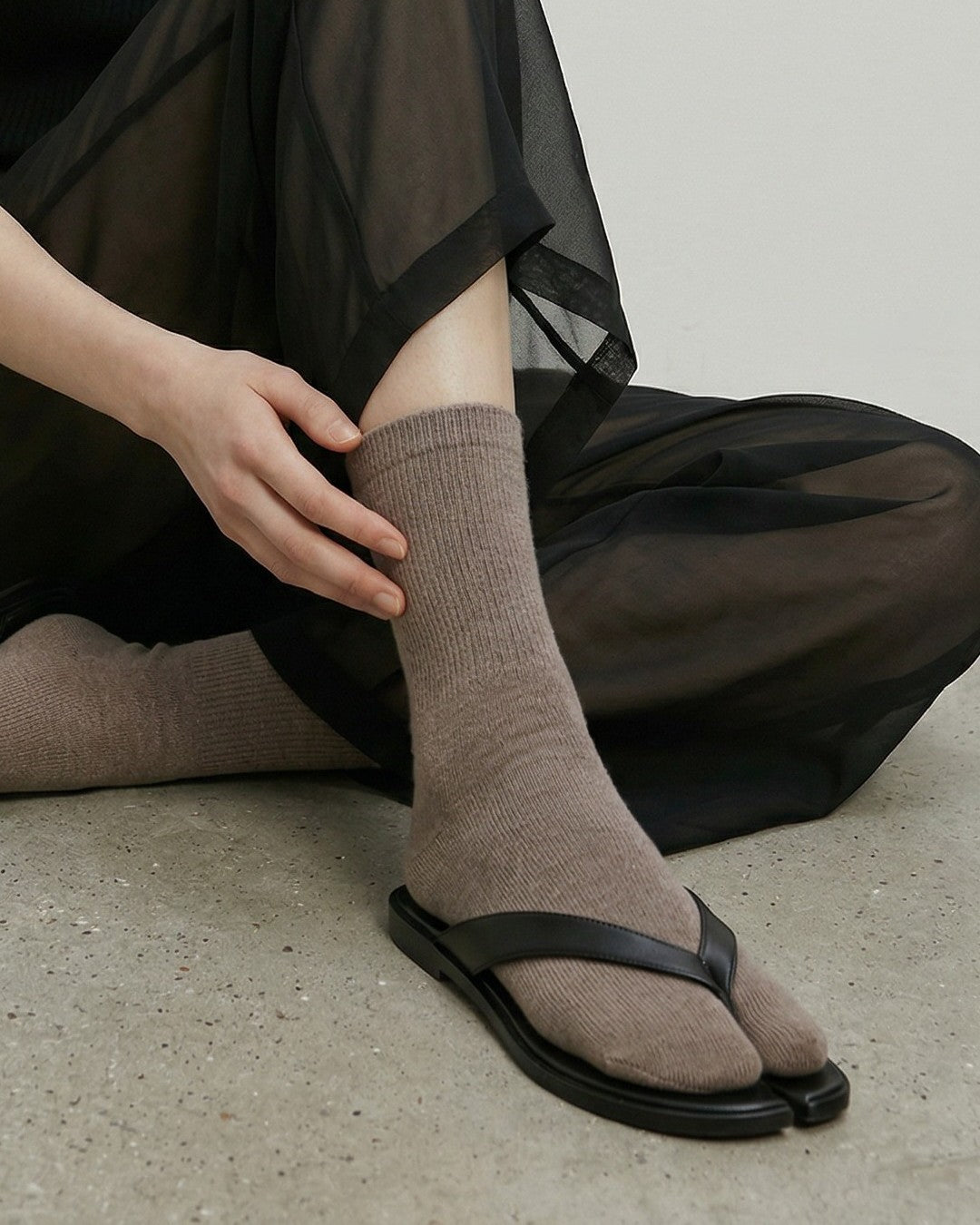 SUNMOOL oatmeal fuzzy tabi socks worn with black thong sandals and sheer trousers