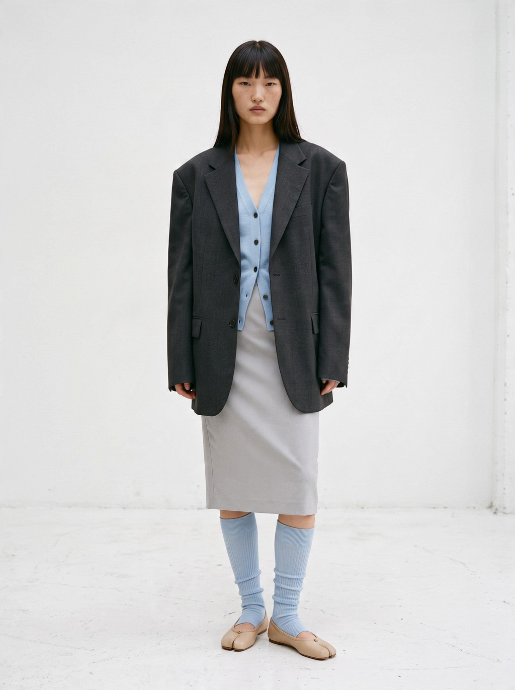SUNMOOL open-toe knee-high ribbed socks in light blue worn with beige tabi shoes, grey skirt, and oversized blazer.
