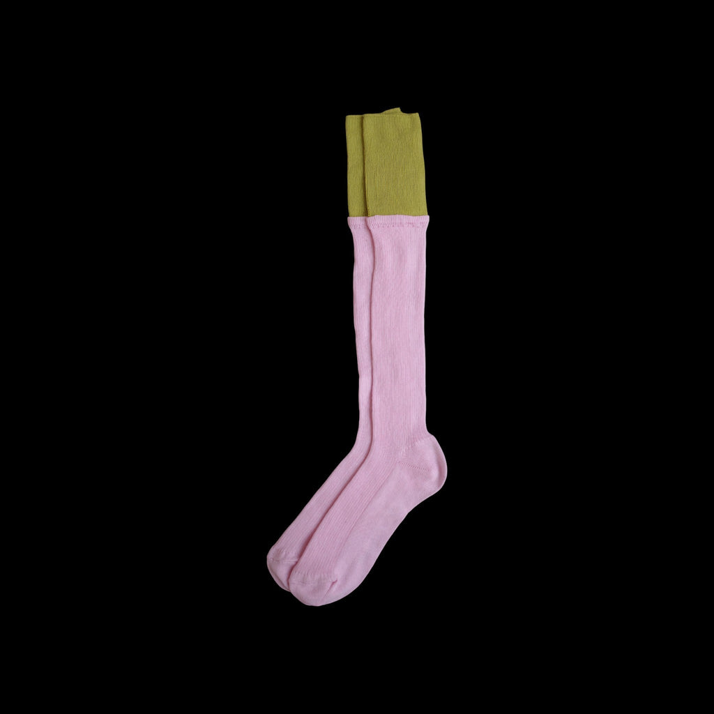SUNMOOL knee-high socks in light pink with a contrasting olive green dip-dyed ribbed cuff on a black background.
