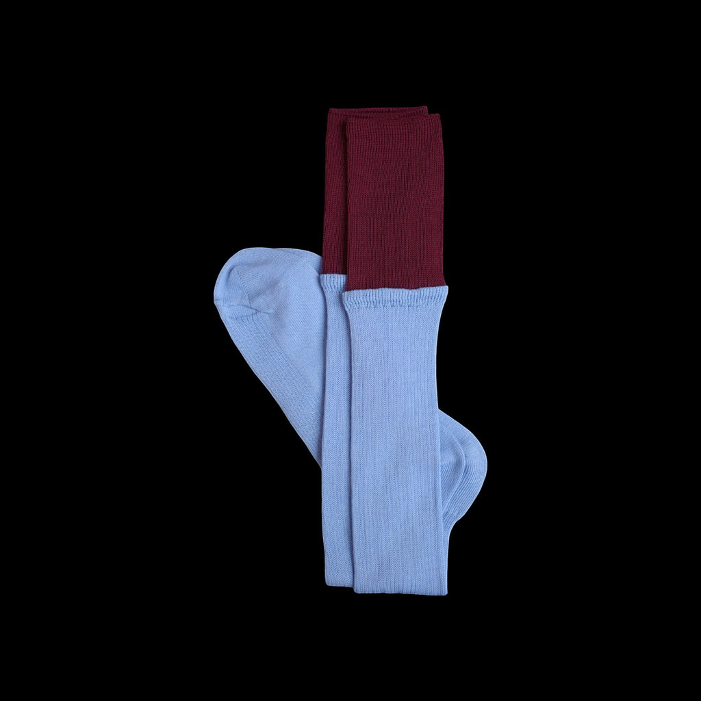 SUNMOOL sky blue knee-high socks with a contrasting deep red dip-dyed ribbed cuff on a black background